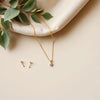 Gold necklace, stud earrings, and bracelet arranged neatly on a light background