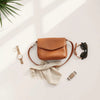 Everyday accessories arranged neatly: watch, earrings, scarf, crossbody bag, belt, and sunglasses
