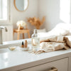 Minimal perfume bottle and mist in soft morning light on a neutral vanity