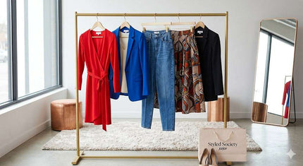 Eye-level view of a stylish gold clothing rack in a bright room, showcasing vibrant outfits including a red wrap dress, a blue blazer, and a patterned skirt, with a branded Styled Society xoxo shopping bag and shoes on a white rug.