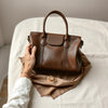 Hands inspecting leather, silk, and gold-tone jewelry with clear material texture details on a neutral surface