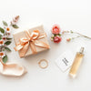 Wrapped birthday gift with ribbon, flowers, and elegant accessories on a light neutral background