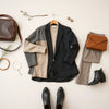 Neatly arranged women’s boutique clothing essentials, including a blazer, dress, trousers, and accessories on a neutral background