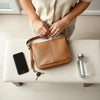 Structured crossbody bag for daily errands next to essentials like keys, phone, and a water bottle