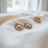 Pair of distinctive dangling earrings on neutral fabric with soft natural light