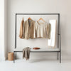 Neatly arranged calm-toned clothing pieces on a minimalist wardrobe rack with soft natural light