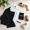 Neutral-toned women’s wardrobe essentials laid out with a blazer, shirt, skirt, jeans, belt, and simple accessories.