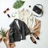 Neatly styled clothing and accessories laid out on a minimal table in soft daylight