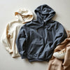 Assorted cozy hoodies in muted colors laid on a neutral surface with soft fabric texture visible