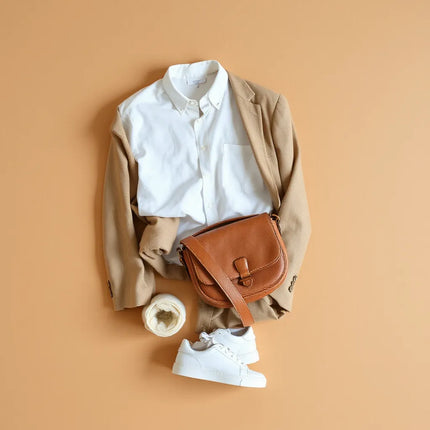Neutrals capsule wardrobe layout with button-up, knit sweater, trousers, sneakers, and crossbody bag