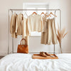 Neatly styled women’s outfits on a minimal clothing rail with handbag and accessories