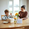 Wrapped mothers day gift box, flowers, and card on a table with warm natural light