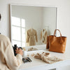 Neutral outfit with a small watch, delicate necklace, and earrings on a minimalist vanity table