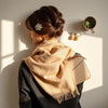 Neatly styled accessories on a neutral surface, including earrings, a hair accessory, and a scarf