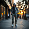 Person in layered casual streetwear outfit with jacket, joggers, and clean sneakers on a city sidewalk