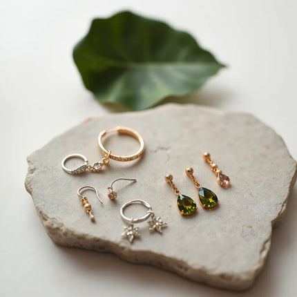 Fashionable earrings featuring studs, hoops, and delicate drops arranged neatly on a neutral surface