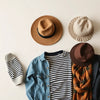 Assorted stylish hats laid out with outfit pieces like denim, blazer, and scarf for coordinated looks