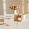 Wrapped gift, birthday and thank-you cards, and small flowers on a clean tabletop