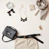Statement jewelry, mini bag, and belt styled together on a neutral background for a confidence-boosting look