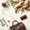 Necklace, earrings, watch, handbag, wallet, scarf, and sunglasses arranged in a neat fashion flat lay.