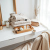 Minimal vanity setup with skincare, accessories, and folded clothing in soft natural light