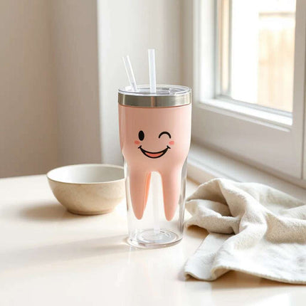 Happy tooth tumbler with straw on a clean surface beside a microfiber cloth and small bowl of water