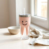 Happy tooth tumbler with straw on a clean surface beside a microfiber cloth and small bowl of water