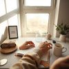 Person resting hands on a closed journal at a bright window, creating a calm reset atmosphere