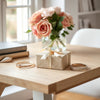 Elegant wrapped gift box with satin ribbon and a fashion accessory on a light wood table