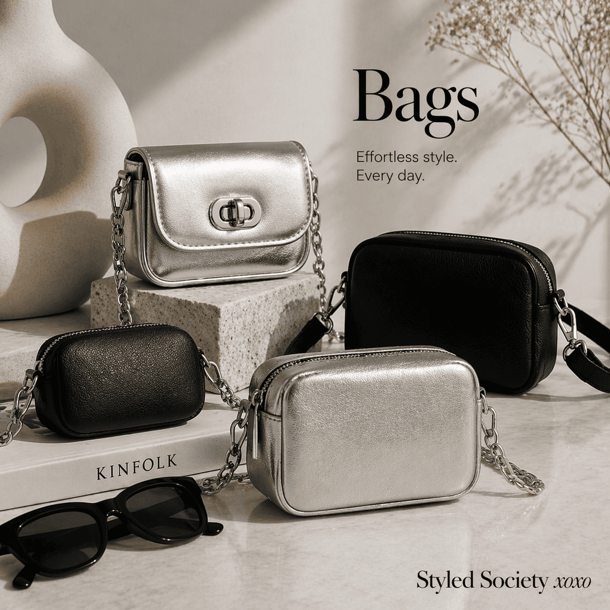A styled lifestyle shot of two silver and two black mini crossbody bags with chain straps, resting on a table alongside sunglasses and a Kinfolk book. Text reads: Bags. Effortless style. Every day. Styled Society xoxo.